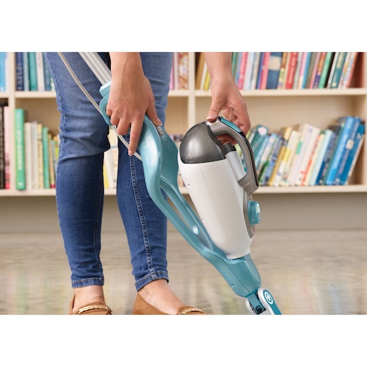 BLACKDECKER BHSM169DSM steam mop with detachable handheld cleaner in use, person removing handheld unit, indoor setting.
