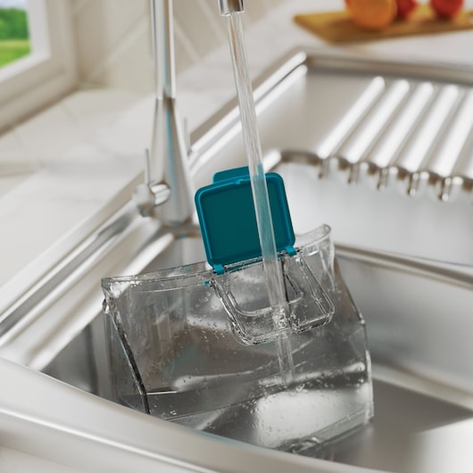 BLACKDECKER BHSMP2314 transparent water tank with blue lid being filled under kitchen faucet.