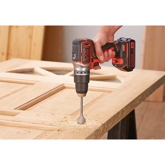 BLACK+DECKER BL188E2K cordless drill in use, drilling a hole in a wooden door, close-up view.