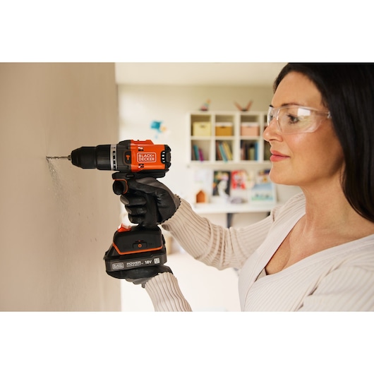 Photo of BLACKDECKER cordless drill BLD683D1 in use, drilling into indoor wall, person wearing work gloves.