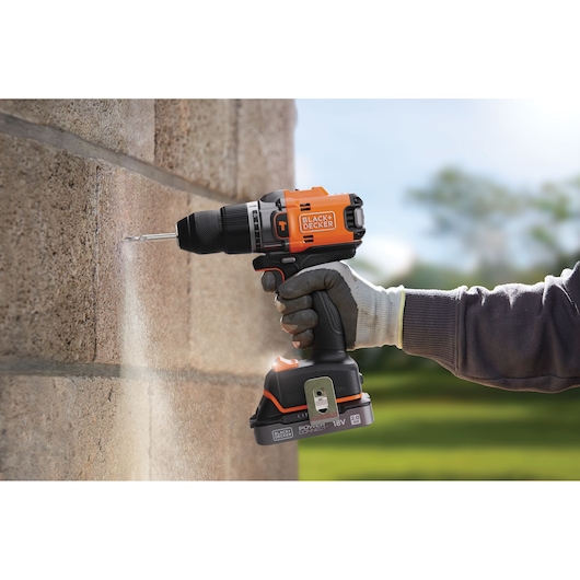 BLACKDECKER BLD683D1 cordless drill used on stone wall, orange and black design, outdoor setting.