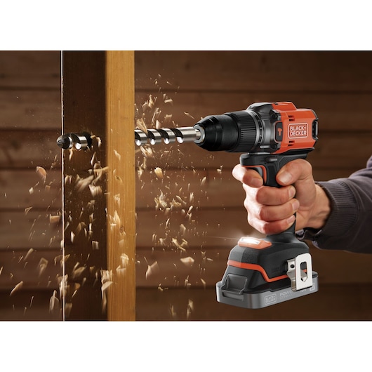 BLACKDECKER BLD683D1 cordless drill in use boring through wood, visible sawdust flying.