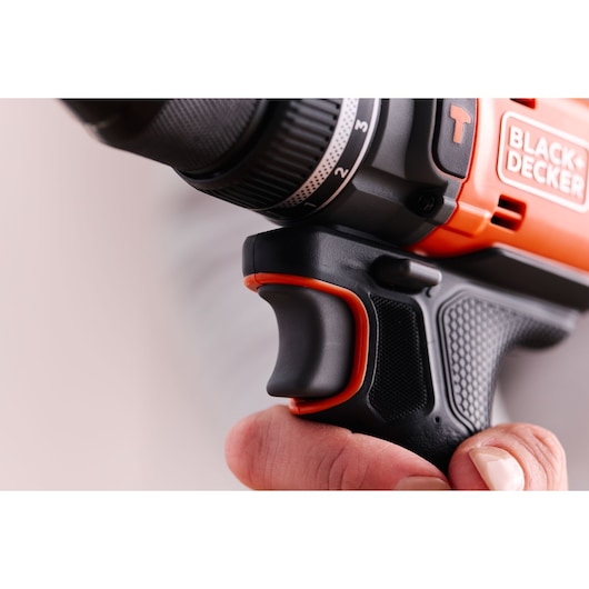 Close-up side view of BLACK+DECKER BLD683D1 drill grip and trigger held by a hand, showing textured black and orange handle.