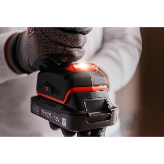 Close-up photo of BLACK+DECKER BLD683D1 18V lithium power tool battery with indicator light, held by gloved hand.