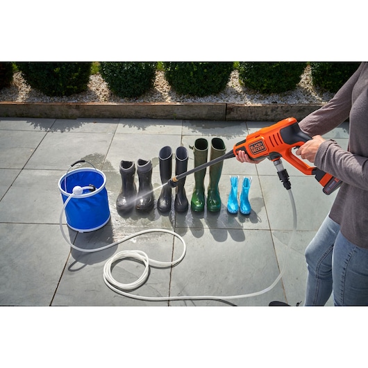 Photo of BLACKDECKER portable pressure washer BZOIHK2 cleaning boots on a patio, with a blue water bucket.