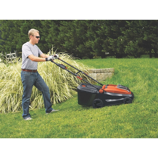 BLACKDECKER CLM3820L1 cordless lawn mower, orange and black, in use on green grass outdoors.