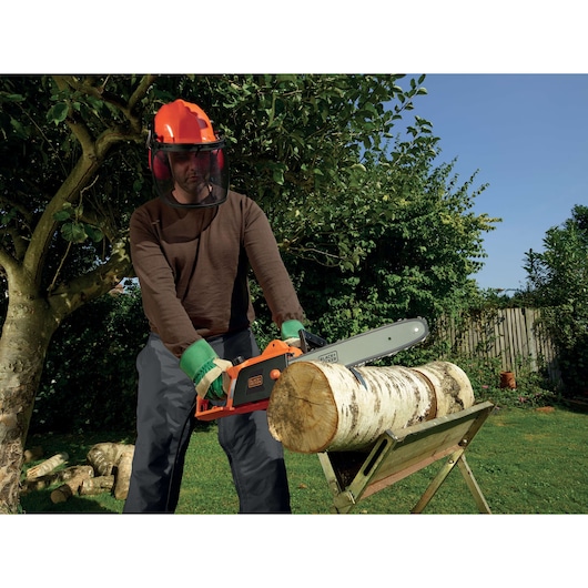 BLACKDECKER CS1840 chainsaw cutting log outdoors, user wearing protective gear, product category photography.