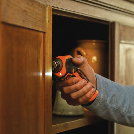BLACKDECKER CS3652LC cordless screwdriver in use on wooden cabinet door.