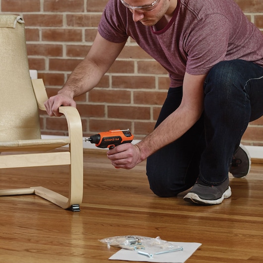 BLACKDECKER CS36BSC cordless screwdriver used to assemble a light wood chair, indoor setting, hardwood floor.