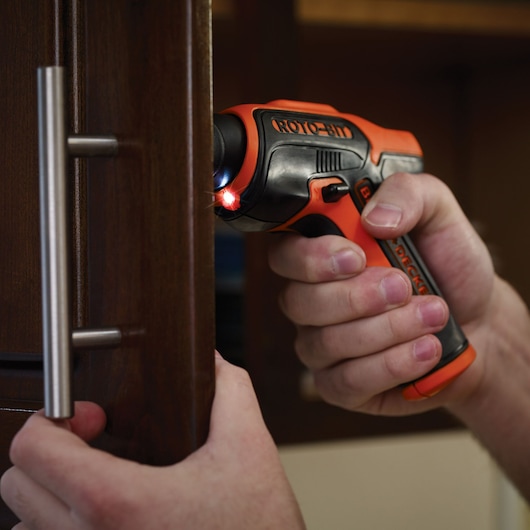 BLACKDECKER CS36BSC cordless screwdriver with LED light in use on a cabinet handle.
