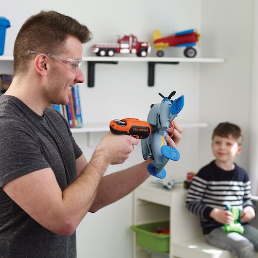 Photo of BLACKDECKER CS36BSC toy drill being used to assemble a blue plastic airplane in a child's playroom.