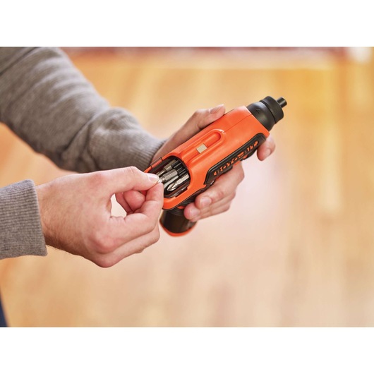 Photo of BLACKDECKER CS36BST orange cordless screwdriver in hand, showing integrated bit storage compartment open.