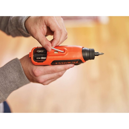 BLACKDECKER CS36BST orange cordless screwdriver with bit storage being loaded, close-up photography.