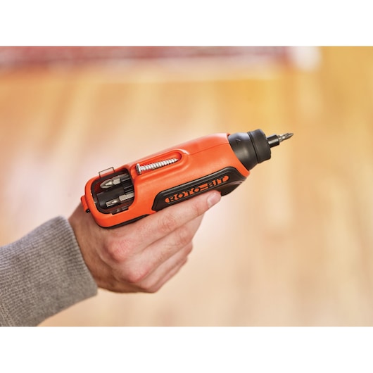 BLACKDECKER CS36BST cordless orange and black screwdriver with bit storage held in hand, side view.