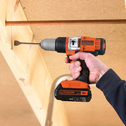 BLACK+DECKER EGBHP188BK cordless drill being used to drill into wood, shows side angle and 18V lithium battery.
