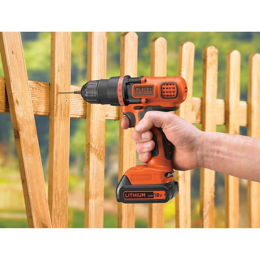 BLACKDECKER EGBL18K cordless drill being used to screw into wooden fencing outdoors.