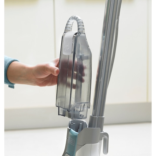 Photo of BLACK+DECKER FSM16CD steam mop in use, showing hand removing the transparent water tank.