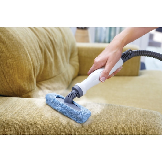 BLACKDECKER FSMH1321JSM steam cleaner with blue cloth cleaning sofa upholstery, close-up.