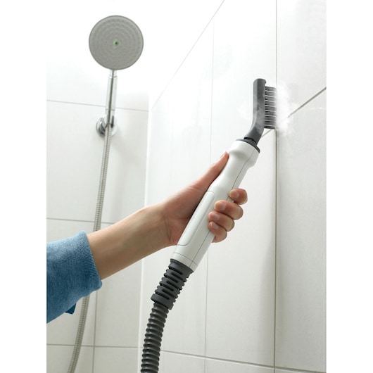 BLACKDECKER FSMH1351SM steam cleaner used on shower tile grout, handheld close-up.
