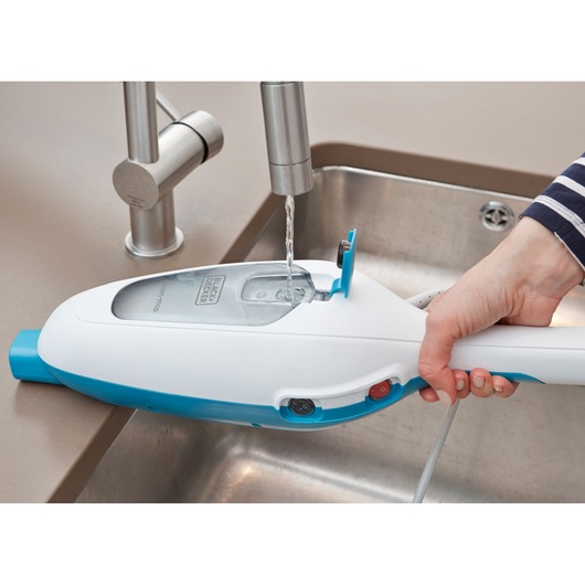 BLACK+DECKER FSMH13ENVC1 steam mop being filled with water at a sink, close-up of water tank and hand.