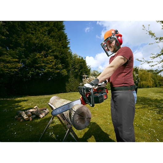 BLACKDECKER GKC3630L20 cordless chainsaw cutting log outdoors, person wearing safety gear.