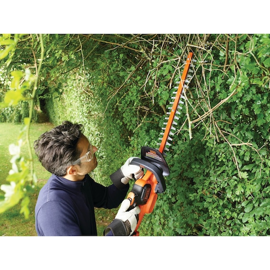 BLACKDECKER GTC18502PC hedge trimmer used in garden trimming branches.