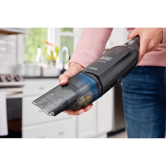BLACKDECKER HLVC320J11 handheld vacuum cleaner in use, black body, cleaning kitchen countertop.