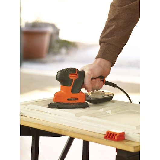 BLACKDECKER KA2000 detail sander with black and orange body shown sanding a wooden surface.