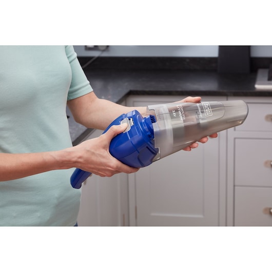 Photo of BLACK+DECKER NVC115WA handheld vacuum cleaner in blue, being emptied over a kitchen counter.