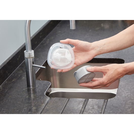 Photo of person holding BLACKDECKER NVC115WA vacuum filter parts over a kitchen sink.