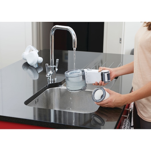 BLACKDECKER PV1820L handheld vacuum being cleaned at a kitchen sink, filter and dust container visible.