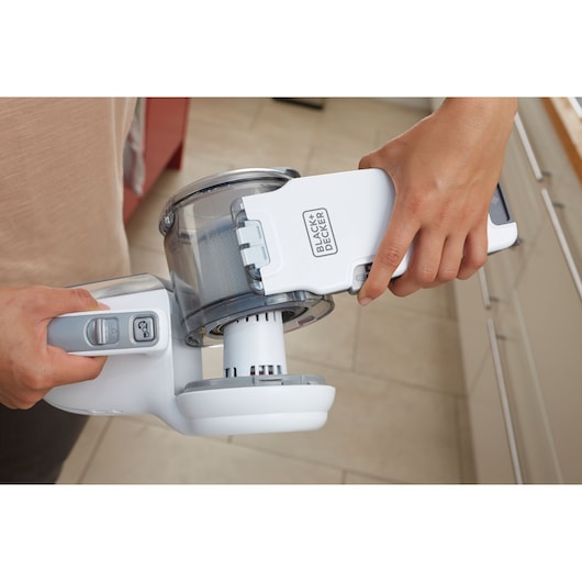 Photo of hands opening BLACK+DECKER PV1820L handheld vacuum cleaner dust compartment in a kitchen.