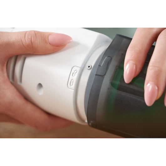 Close-up of BLACKDECKER REVHV8C handheld vacuum being opened, showing hands holding white body and black dustbin.
