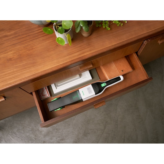 BLACKDECKER REVHV8C handheld vacuum stored in wooden drawer, white and green design, top angle.