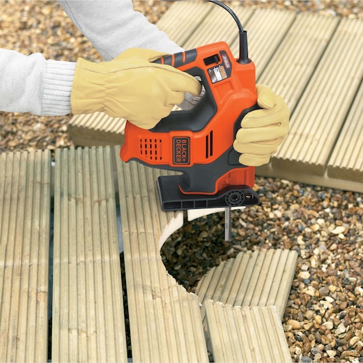 BLACK+DECKER RS890 powered saw cutting curved wood outdoors, handled by person with yellow gloves.