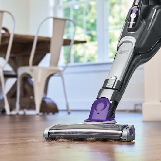 BLACKDECKER SVJ520BFSP cordless vacuum cleaner with purple accents cleaning pet hair from a hardwood floor.