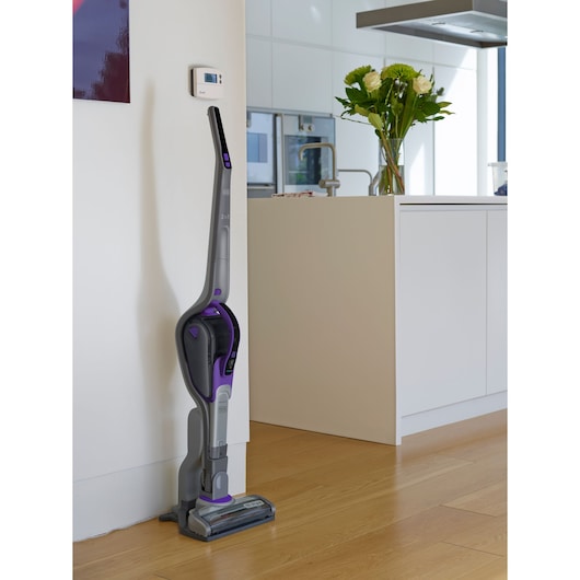 BLACK+DECKER SVJ520BFSP cordless stick vacuum cleaner with purple accents standing upright in a modern kitchen.