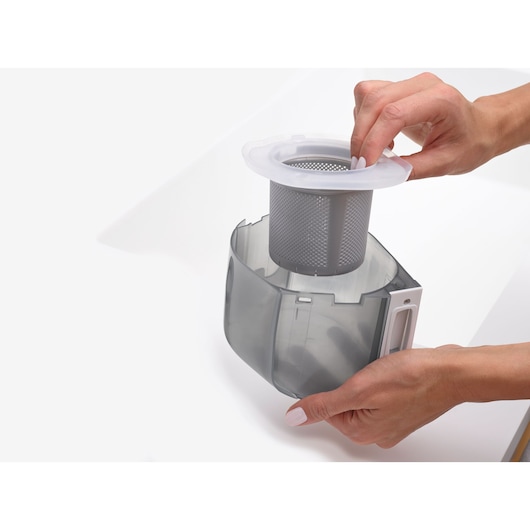 Photo of BLACKDECKER VSPF10CF vacuum filter being removed from transparent dust canister, close-up view.