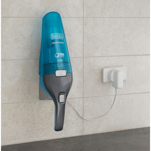 Photo of BLACK+DECKER WDC215WA handheld vacuum in blue and grey, wall-mounted and charging on a tiled wall.