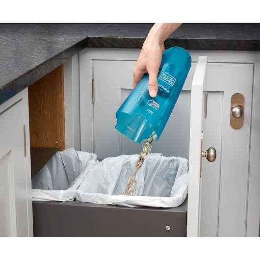 BLACK+DECKER WDC215WA handheld vacuum with blue dustbin being emptied into a kitchen trash bin.