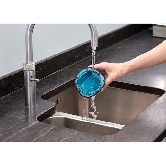 Photo of BLACKDECKER WDC215WA vacuum filter being rinsed with water in a kitchen sink.